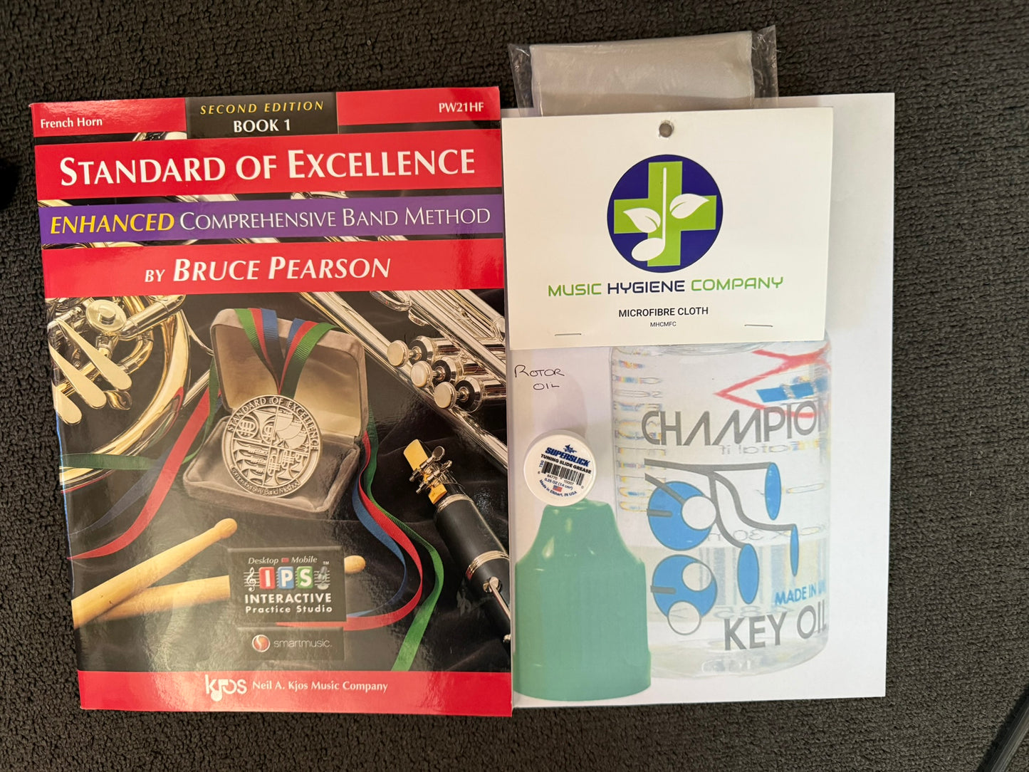 French horn student bundle with book, grease, oil, and cleaning cloth.